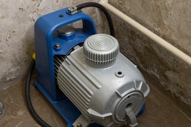 A blue and silver portable electric water pump draining a flooded basement floor.