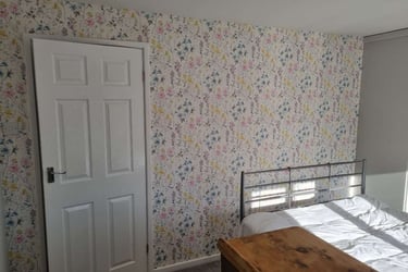 Freshly wallpapered wall of a bedroom, with various plants on a white/cream background.