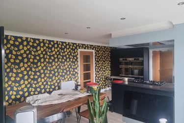 Kitchen in a residential home, with a large wall covered in dark-blue and lemon motif wallpaper.