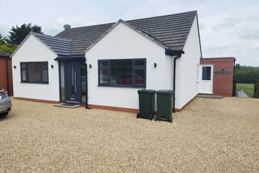 Exterior of a painted-white bungalow, with a black-tiled roof and black detailing.
