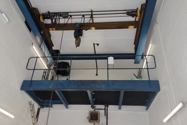 An industrial pure-white, freshly-painted room, with a high ceiling and lift-machinery.