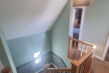 Finished top of staircase, with painted mint-green walls and white ceiling.