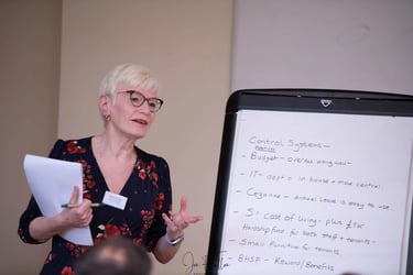 A professional woman presenting business control systems on a white flipchart during a meeting.