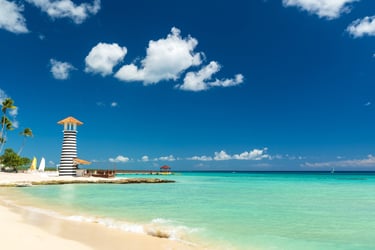 Scenic beach with turquoise water and striped lighthouse in Bayahibe, Dominican Republic