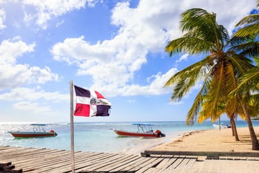 Saona Island Dominican Republic beach with flag palm trees boats and turquoise Caribbean sea