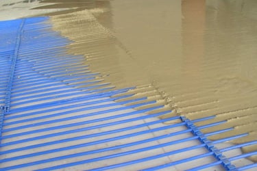 Self-leveling floor compound being poured over radiant floor heating capillary tube