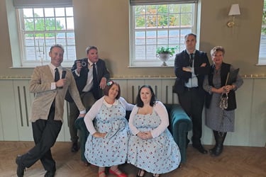 A group of event staff and performers in vintage 1950s attire posing for a photo at a retro-themed party.