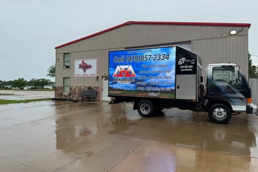 Digital mobile billboard truck for Arkansas cheer and dance advertising parked in front of a sports facility.