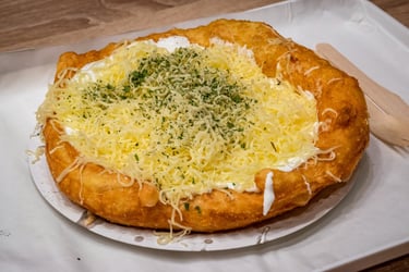 a lángos with cheese and cheesecakes on a plate