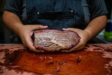 pitmaster holding brisket, showing smoke ring and fat marbling