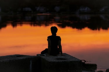 Person sitting peacefully at sunset during a spiritual guidance consultation focused on support