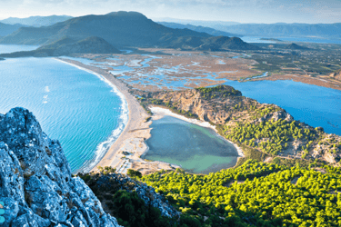 a person standing on a mountain top with a view of Iztuzu Beach