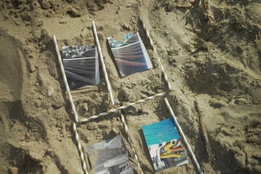 Film still from Excitement by Tina Bikic showing photographs arranged in sand and framed a storyboard with stripped sticks.