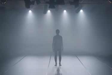  Performer standing under multiple stage lights in fog – film still from Lingua Materna by Tina Bikic