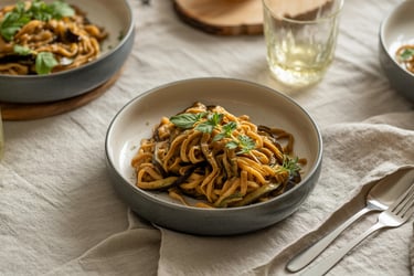 a table with a bowl of noodles and a glass of wine