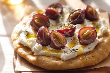 a pizza with grapes and cheese on a wooden board