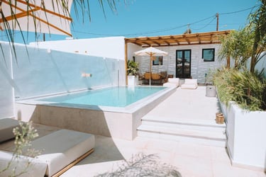 Luxury villa patio with a private infinity pool, sun loungers, and a shaded outdoor lounge area.