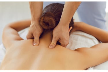 Terapeuta aplicando massagem com os polegares na região cervical de uma paciente deitada em uma maca