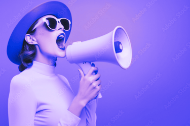 a woman in a hat and sunglasses is holding a megaphone