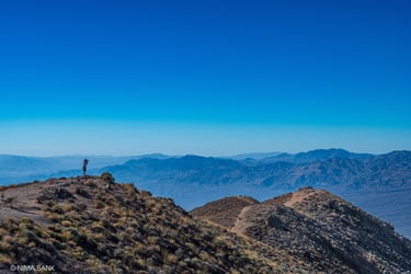 a man overlooking dantes peak with more hazy mountains in the distance in death valley california