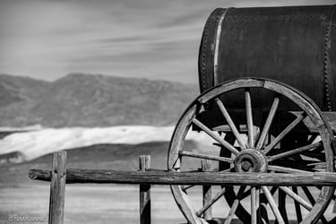 black and white wooden wagon with mountains in background in death valley califormia