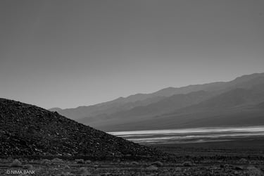 a spooky hazy black and white mountain range and salt basin in death valley