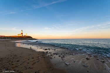 the montauk lighthouse at the end of the beach at sunset