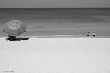 beachgoers in the gulf of mexico and under a beach umbrella and sand in naples florida