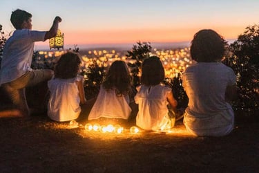 a family sitting on a hill overlooking a city at night