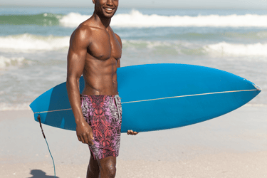 a man in a swimsuit holding a surfboard