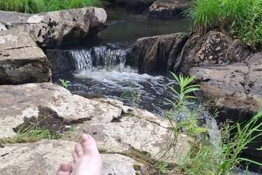 bare feet next to a babbling brook