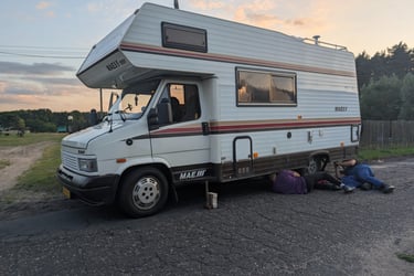 Polish car mechanics working on a broken campervan at the roadside near the German border.