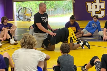 a group of people sitting on a wrestling mat