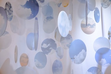 Photo of small hanging translucent discs with cloud images on them.