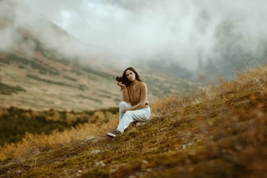 a woman sitting on a hill with a camera