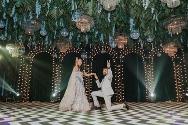 a man and woman standing in front of a large chandelier