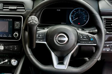 A Nissan steering wheel featuring an attached handicap driving aid hand control for accessible vehicle operation.