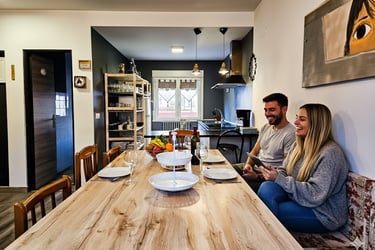 Living room and kitchen of a tourist house, a man and woman sitting at a table with plates of food