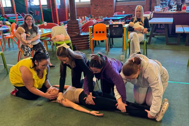 Group of learners practising first aid skills on a casualty during a practical training session