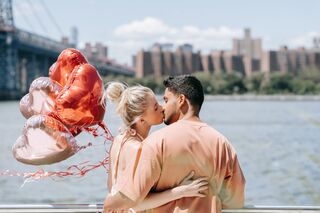 a man and woman kissing on a bridge over a river
