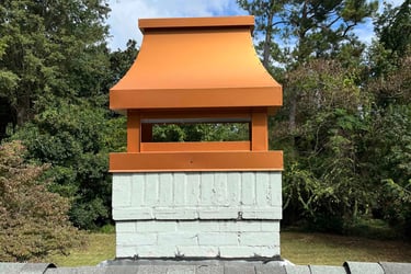 Custom copper-colored metal chimney shroud installed on a white brick chimney cap atop a shingle roof.