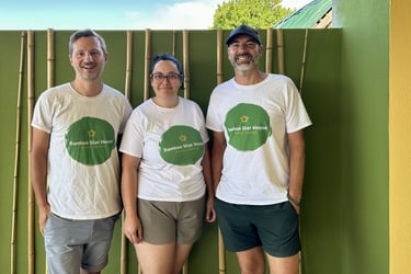 Three people wearing Bamboo Star House Madeira shirts standing in front of a green bamboo wall.