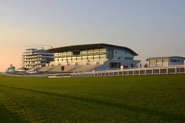 Epsom racing grandstand and green turf track at sunset.