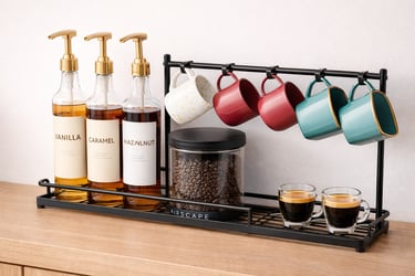 Modern coffee station organizer with syrup dispensers, bean canister, and colorful mugs on a countertop.