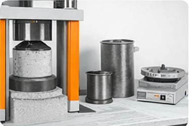 Prensa hidráulica y moldes para ensayos de resistencia de hormigón.