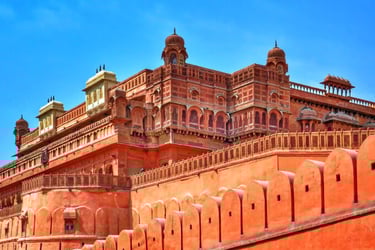 Intricate red sandstone architecture of Junagarh Fort in Bikaner, Rajasthan under a clear blue sky.
