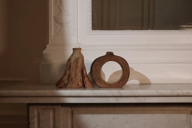 Hand-turned wooden vessels and decorative bud vases displayed on a shelf with moody interior lighting.