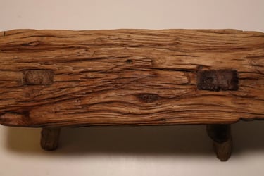 Rustic reclaimed wood bench featuring a weathered natural grain texture and sturdy timber legs.