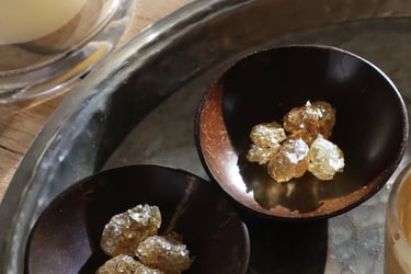 Golden frankincense resin pieces in small dark wooden bowls on a rustic metal tray.