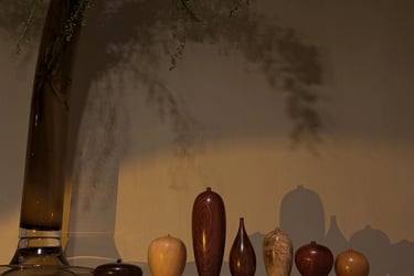 Hand-turned wooden bud vases in various grains and shapes displayed on a shelf with moody lighting.